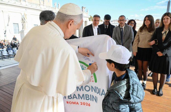cq5dam.thumbnail.cropped.1500.844 Pope Leo signs a flag bearing the 2026 World Children's Day logo (@Vatican Media)