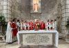 St. James Vicariate Marks 70 Years in Jerusalem Amid Faith, Memory, and Challenge Catholic Mass scene with priests in red and white vestments around a decorated altar, candles lit, in a stone chapel.
