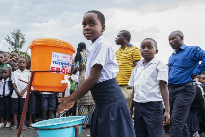 con201953500 Children in the DRC wash their hands before going to class. In 2019, handwashing kits were distributed to schools in order to prevent the spread of Ebola. (Credit CRS)