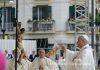 Pope in Pompeii: Leo XIV marks first anniversary with plea for peace and an end to “fratricidal hatred” Catholic priest in white vestments blesses a suspended crucifix during an outdoor street procession, with a carved statue hanging from a pole nearby and onlookers in the background.