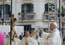 Pope in Pompeii: Leo XIV marks first anniversary with plea for peace and an end to “fratricidal hatred” Catholic priest in white vestments blesses a suspended crucifix during an outdoor street procession, with a carved statue hanging from a pole nearby and onlookers in the background.