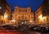 Christian and Dharmic Leaders Gather in Rome to Advance Fraternity, Dialogue, and Peace Across Europe Night view of a grand neoclassical building in a cobblestone square, illuminated by streetlights with cars parked along both sides.
