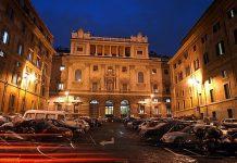Christian and Dharmic Leaders Gather in Rome to Advance Fraternity, Dialogue, and Peace Across Europe Night view of a grand neoclassical building in a cobblestone square, illuminated by streetlights with cars parked along both sides.