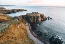 Aberdeen Bishop Expands Traditional Latin Mass Access as Illicit Episcopal Consecration Looms in Scotland Coastal cliffs with a castle perched on a rocky headland overlooking the sea at sunset contrasted with warm earth tones and calm water edge nearby